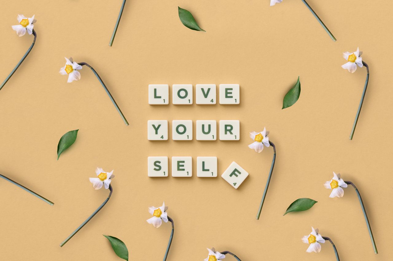 The Art of Drawing Readers In: Your attractive post title goes here Scrabble tiles spelling 'Love Yourself' surrounded by flowers and leaves on a flat surface.